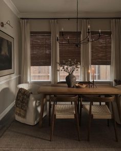 a dining room table with two chairs and a vase on top of it in front of the window