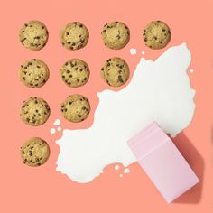 chocolate chip cookies next to a pink carton of milk on a pink background with white paint