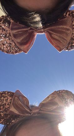 two girls with bows on their ears looking up at the sky and sun shining through them