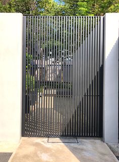 a bike is parked in front of an iron gate that leads to a driveway with trees behind it