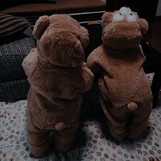 two teddy bears sitting on top of a bed