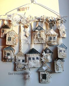 there are many small houses hanging on the wall with ribbons and decorations attached to it