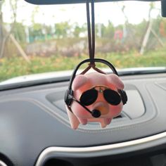 a pink piggy bank with sunglasses hanging from it's headrest in a car