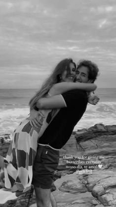 a man hugging a woman on the beach with an ocean in the backgroud