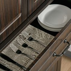 an open drawer with plates and utensils in it