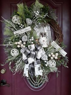 a wreath on the front door decorated with pine cones and evergreens