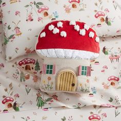 a mushroom house pillow on top of a bed