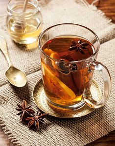 a glass cup filled with tea and anise on top of a table