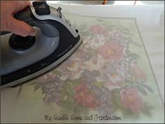 a person using an iron on top of a flowered table cloth with a floral design