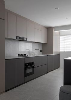 a modern kitchen with grey cabinets and white counter tops, along with a black chair