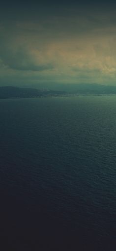 an airplane flying over the ocean under a cloudy sky