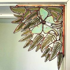 a clock that is hanging on the side of a wall next to a plant with green leaves