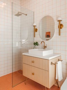 a white sink sitting under a bathroom mirror next to a walk in shower and toilet