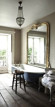 a bathroom with wooden floors and an old fashioned tub in the middle, next to a large window