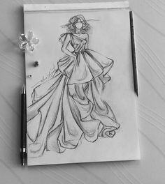 a drawing of a woman in a dress on a piece of paper next to a pen