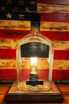 a bottle of gentleman jack sitting on top of a wooden table next to an american flag