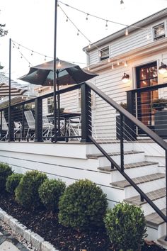 an outdoor patio with chairs and umbrellas next to a house in the evening light