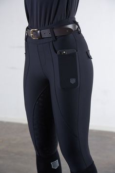 a woman in black riding pants with her hands on her hips