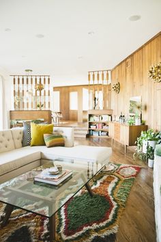 a living room filled with furniture and lots of wood paneling on the wall behind it