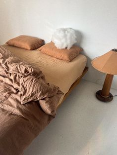 an unmade bed with two pillows on it and a lamp next to the bed