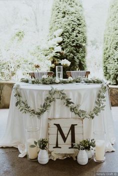 the table is set up with candles and greenery