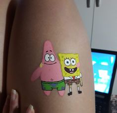 a person with a spongebob sticker on their arm next to a laptop