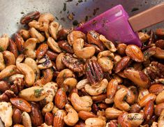 nuts are mixed together in a bowl with a wooden spoon