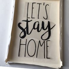 a piece of paper with the words let's stay home written in black ink