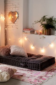 a living room filled with lots of furniture and lights hanging from the wall above it