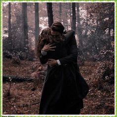 a man and woman hugging in the woods