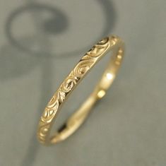 a gold wedding band with scrolls on it