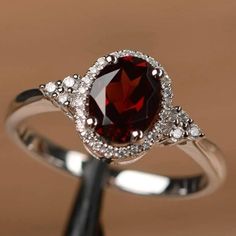 a ring with a large red stone surrounded by white diamonds