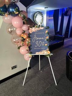 a welcome sign with flowers and balloons in the shape of a wreath is on display