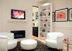 a living room with two white chairs and a fire place in the corner on one wall