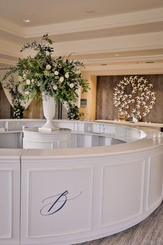 a large white vase with flowers on top of it in front of a reception counter