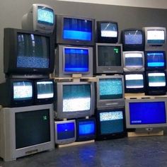 a bunch of tvs that are stacked on top of each other in a room