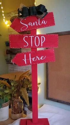 a wooden sign that says santa stop here and there is a potted plant next to it