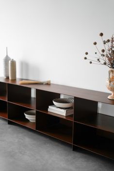 a vase with flowers on top of a wooden shelf