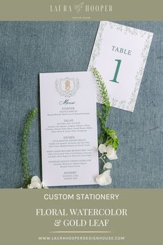 the wedding stationery is displayed with white flowers and greenery on blue linens