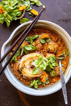 a bowl filled with meat and vegetables on top of a table next to chopsticks