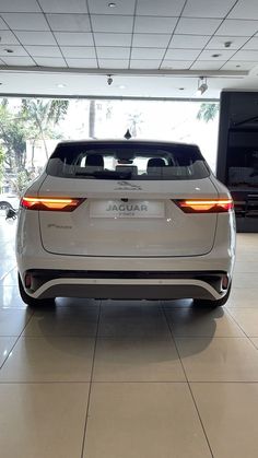 the rear end of a white car in a showroom with its lights turned on