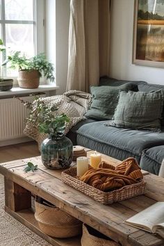 a living room with a couch, coffee table and potted plants on it in front of a window