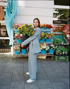 a woman standing in front of a bunch of flowers