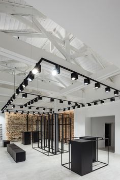 an empty room with several black tables and lights hanging from the ceiling in front of it