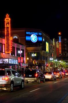 a city street filled with lots of traffic next to tall buildings and neon signs at night