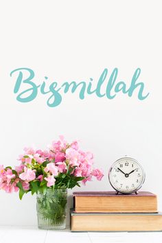 a vase filled with pink flowers sitting on top of a book next to a clock