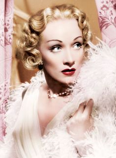 black and white photograph of a woman with feathered shawl over her shoulders, looking at the camera