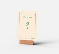 a table number card with a wooden stand on the front and back of it, in green ink