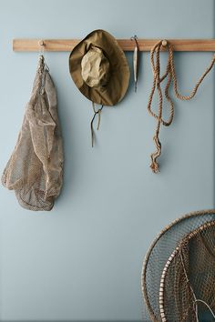 two hats hanging on the wall next to some fishing nets and net bags with hooks