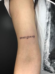 a woman's arm with the words never give up tattooed on her left arm